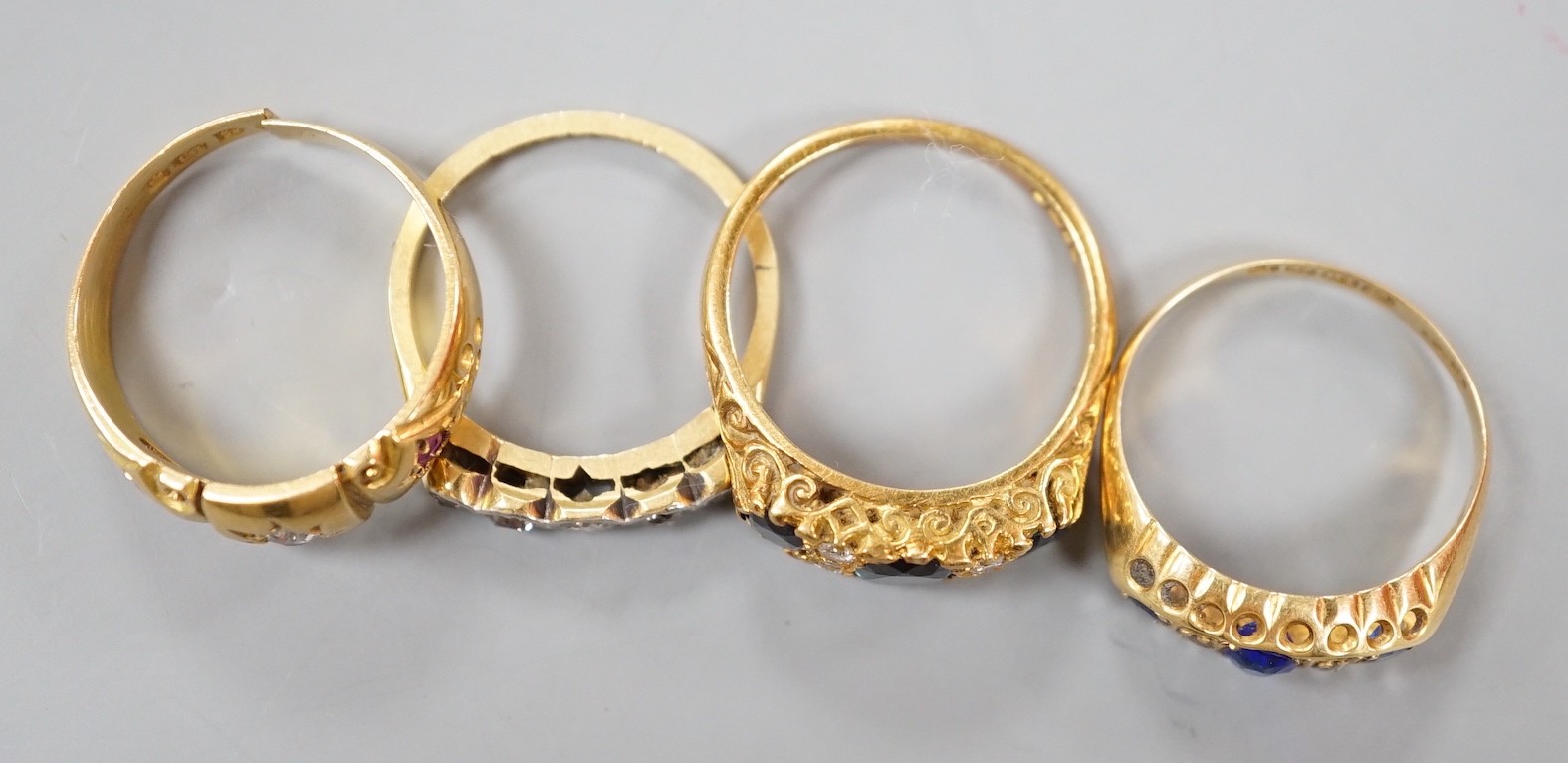 Three early 20th century 18ct and gem set half hoop rings, including ruby and diamond chip, five stone diamond, blue paste and blue stone doublet and diamond chip and a modern 18ct gold sapphire and diamond ring, gross w